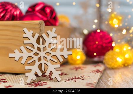 Snowflake carved from wood on a blurred background. New Year card. Stock Photo