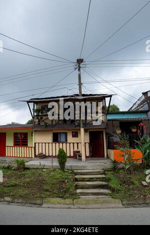 Filandia, Quindio, Colombia - June 5 2022: Metal Pole in Front of a Small YellowColonial House with a Lot of Cables Distributed on Different Sides Stock Photo