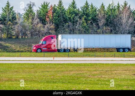 Horizontal shot of a red tractor trailer traveling on a lonely late summer highway. Stock Photo