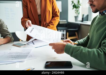 Close-up of teacher of foreign language passing grammar test to young male student before exam or individual work at lesson Stock Photo