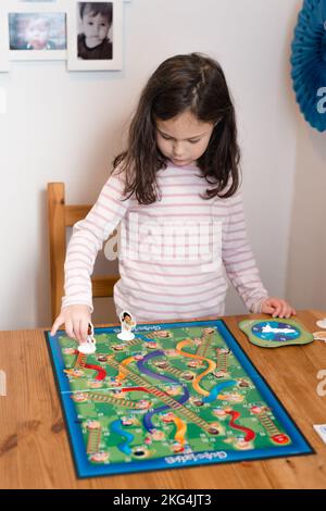young pretty girl playing a board game at home in the kitchen Stock Photo