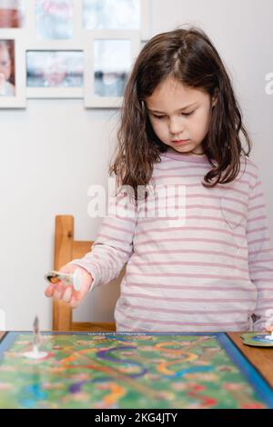 young pretty girl playing a board game at home in the kitchen Stock Photo