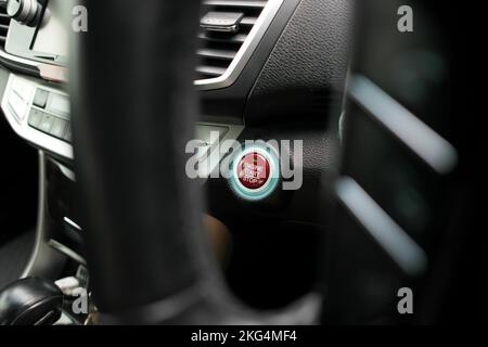 Red engine start stop button with an LED blue light on panel in a automobile Stock Photo