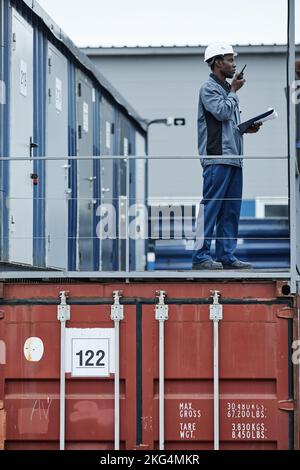 Graphic portrait of male worker standing on containers in shipping docks Stock Photo