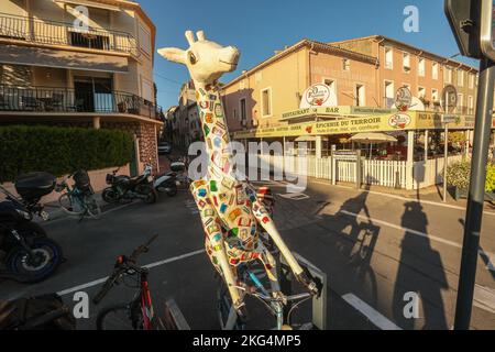 Giraffe,giraffe on a bicycle,art,installation,advertising,bookshop,in,town,of,Meze,Herault,South of France,France,French,harbour,harbor,port,marina,August,summer,mediterannean,mediterranean,Occitanie,Europe,European,