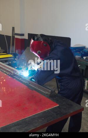 woman working in a workshop welding metal with protection mask and gloves Stock Photo