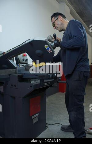mature man working and cutting metal with industrial saw in workshop Stock Photo