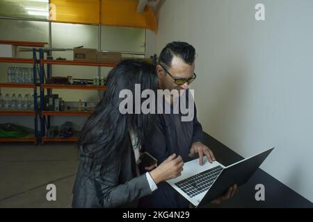 man and executive woman working with a laptop in a workshop Stock Photo