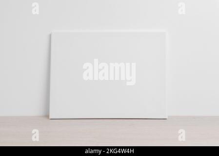 Art canvas in a horizontal position on the floor leaning against a white wall. Clean cloth for mockup art presentation Stock Photo