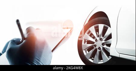 The mechanic is taking notes on paper for analyzing the car problems, auto maintenance service business concept Stock Photo