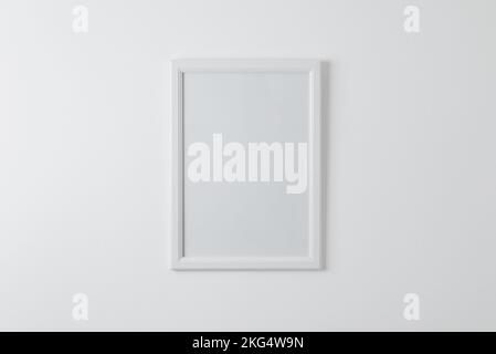 Empty picture frame mockup on clean wall. Blank surface for copy or art presentation. White wooden frame Stock Photo