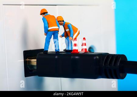 Miniature workmen inspecting an HDMI television socket and plug interface Stock Photo