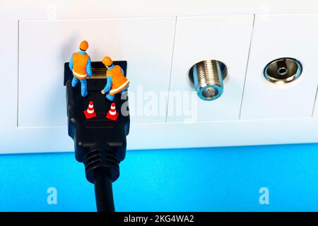 Miniature workmen inspecting an HDMI television socket and plug interface Stock Photo