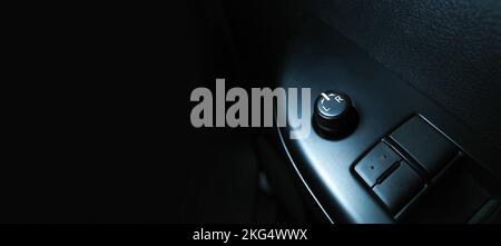 Car wing mirror adjustment switch on armrest panel, panoramic banner with copy space on black background Stock Photo