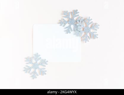 White sheet of paper for congratulations surrounded by snowflakes. christmas pink background Stock Photo