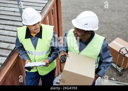 High angle view at two smiling workers carrying boxes up stairs at shipping docks Stock Photo