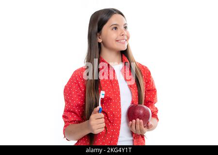 Portrait of caucasian teen girl holds a toothbrush brushing her teeth, morning routine, dental hygiene, isolated on yellow background. Apple vitamins Stock Photo