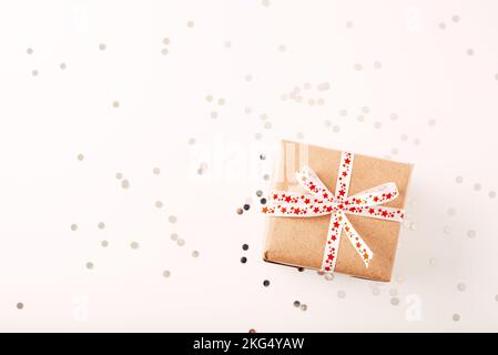 Christmas gift or present and confetti on white table top view. Greeting card with holiday decorations. Stock Photo