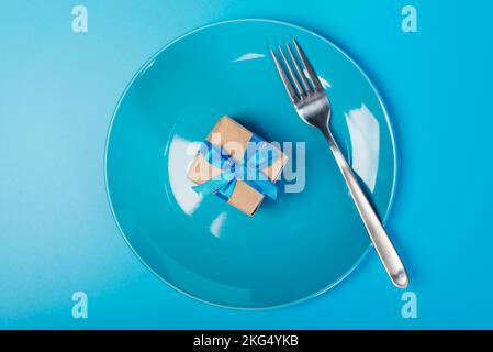 Plate with gift and fork. An empty plate with a small box is a gift. Stock Photo