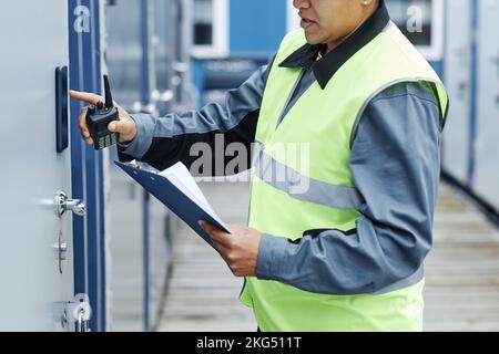 Cropped shot of worker entering key code on storage unit and holding clipboard Stock Photo