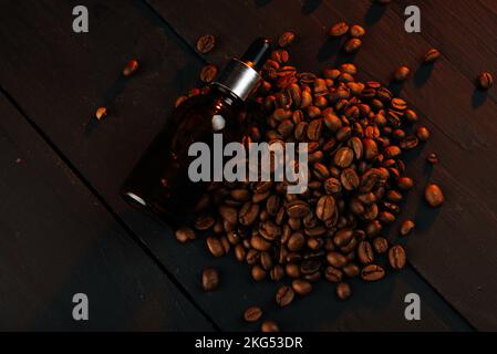 Essential oil with coffee beans on black wood background. Oils for beard. Stock Photo