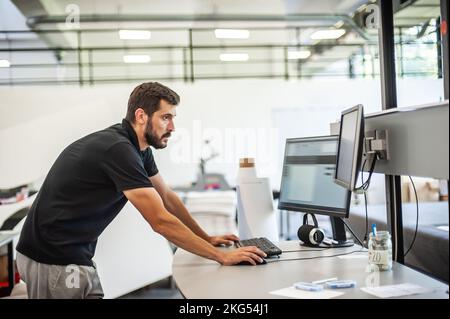 Professional worker printmaker technician operator works in printing press hall and printshop office with many different type of machine Stock Photo