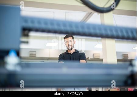 Professional worker printmaker technician operator works in printing press hall and printshop office with many different type of machine Stock Photo