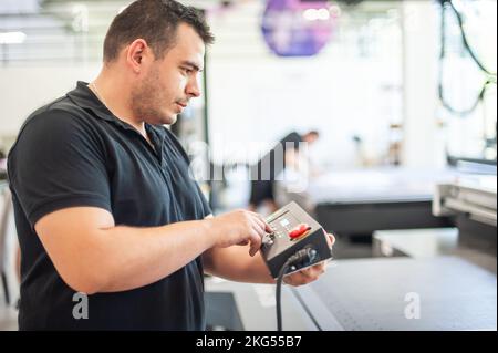 Professional worker printmaker technician operator works in printing press hall and printshop office with many different type of machine Stock Photo