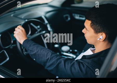 man in wireless headphones driving black car Stock Photo