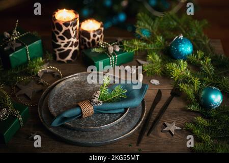 Christmas table setting with empty black ceramic plate and green gift boxes Stock Photo