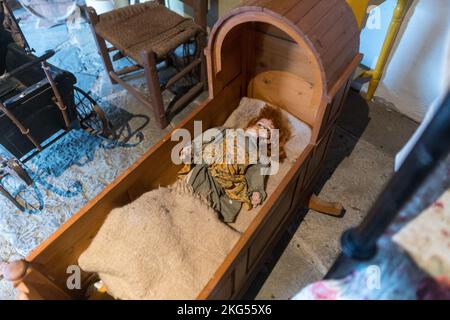 Scary abandoned old baby doll with a cracked head in a cradle Stock Photo