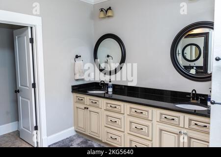 A double bathroom vanity with black granite counter tops and cream custom cabinets Stock Photo