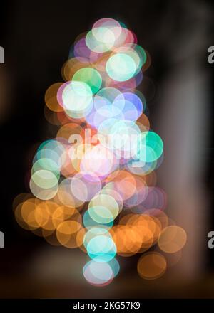 Defocused Image Of Illuminated Christmas Tree Against Black Background Stock Photo