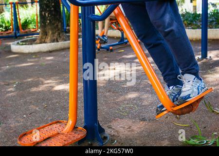 Man's legs swinging on outdoor fitness equipment at Parque Rosinha Cadar in Belo Horizonte, Brazil. Stock Photo