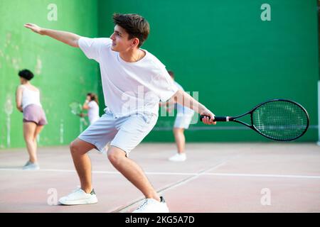 Active man with racket playing frontenis game on outdoor court Stock Photo