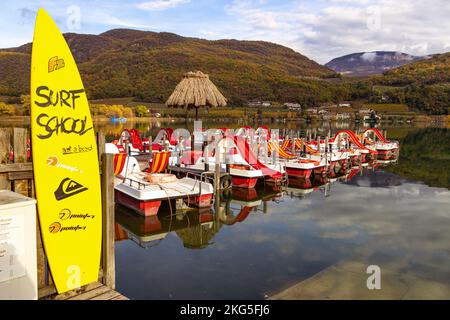 Kaltern, South Tyrol, Italy -14 November 2022 Natural bathing Lake Caldaro in autumn with pedal boat rental and surf school Stock Photo