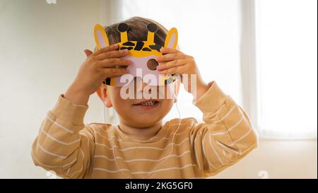 a young mother with her little son play with animal masks to share and enjoy family life inside their home in the living room smiling and having fun Stock Photo
