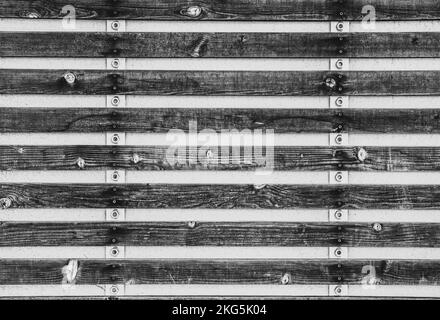 Black and white industrial rustic style background with wood slabs attached to strips of metal with bolts Stock Photo
