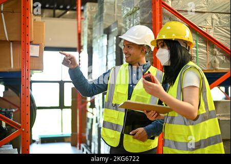 Smart and professional millennial Asian male warehouse supervisor training and working with a young female worker in warehouse. industrial workplace c Stock Photo