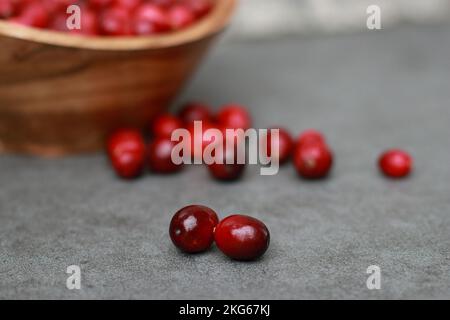 close up of fresh cranberries in a wooden bowl, grey marble table  Stock Photo