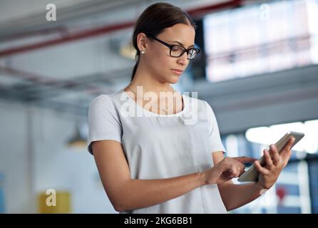 Tech for modern business. Serious young businesswoman using her digital tablet in an industrial space. Stock Photo