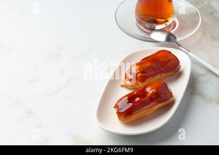 Two caramel eclairs on a white plate Stock Photo