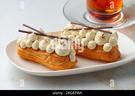 Two eclairs with white custard on whhite plate Stock Photo