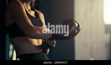 Close-up young woman wearing boxing glove in the gym. Stock Photo