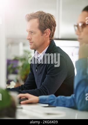 Focused on the task at hand. two colleagues at their desks. Stock Photo
