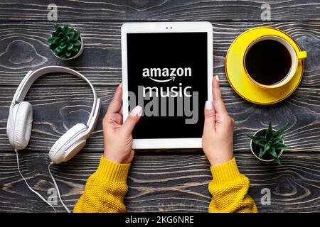 Bangkok, Thailand October 2022 Amazon music online music streaming platform and store, on screen of tablet in hand, wireless headphones, charger capsu Stock Photo