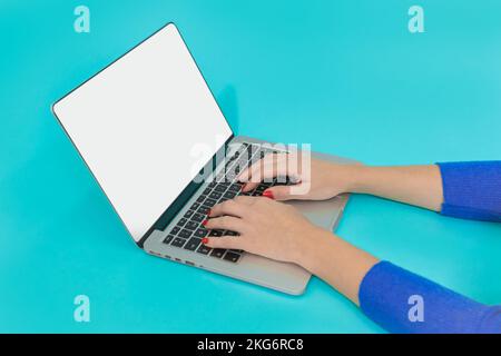Woman hands using laptop with blank display on blue background. Modern workspace concept. Flat lay Stock Photo