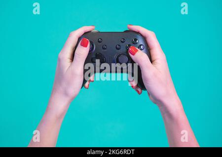 POV of female hands gaming with video game controller gamepad isolated on a blue background studio. Stock Photo