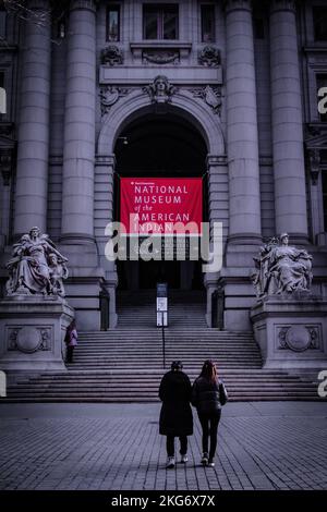 A vertical shot of two women walking in front of National Museum of American Indians, New York Stock Photo