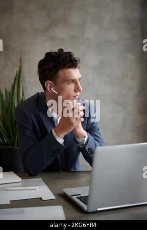 Portrait of young pensive entrepreneur looking through cafe window when having online meeting with team Stock Photo